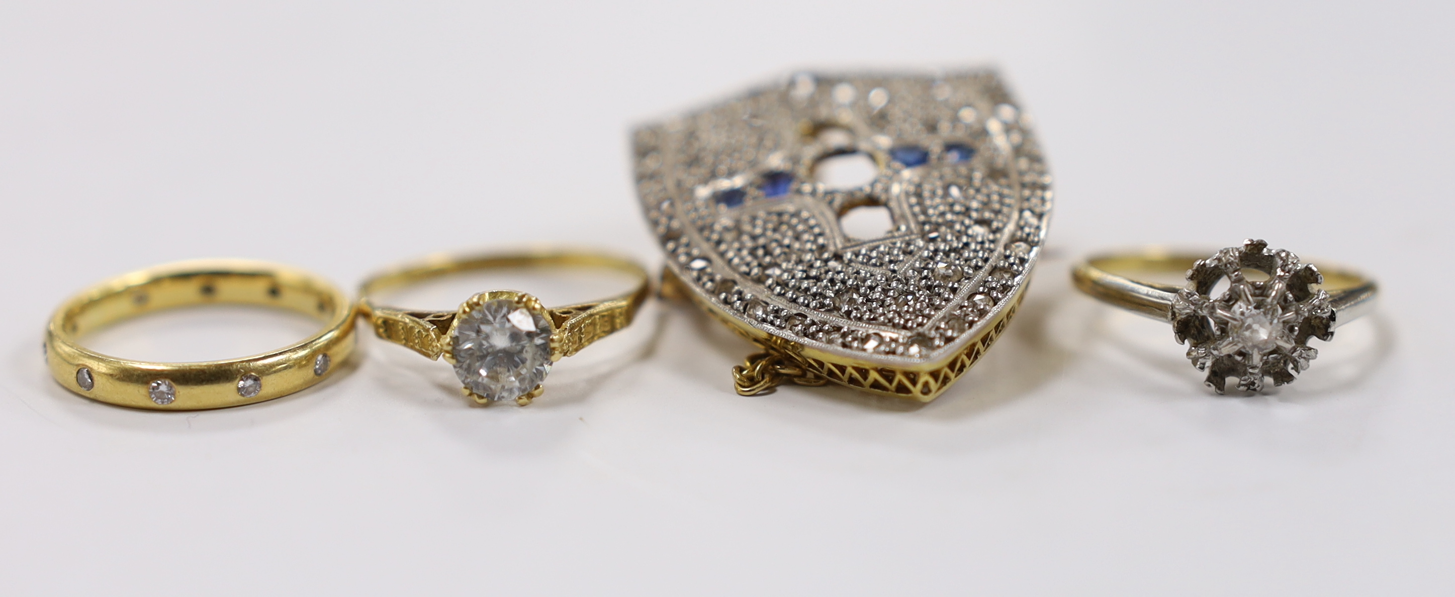 A late 19th century yellow metal, rose cut diamond and sapphire cluster set shield shaped brooch (three stones missing), 35mm and three rings including modern 18ct gold and gypsy set eternity, an 18ct and single stone di